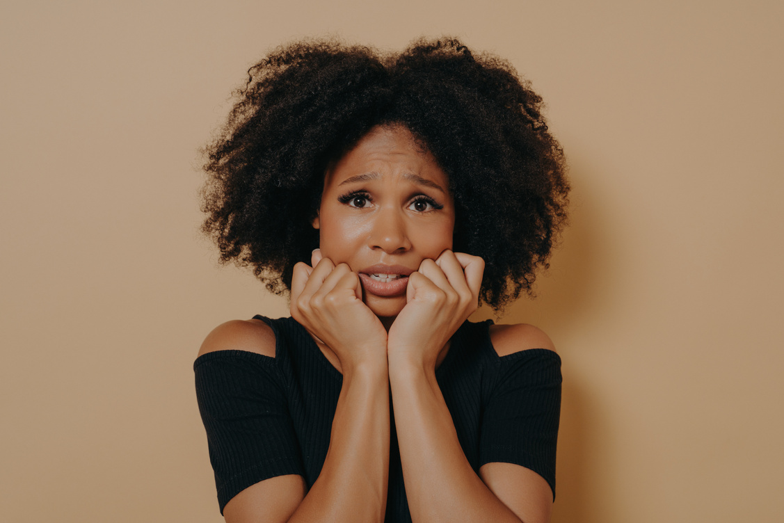 Scared Mixed Race Female Looking Nervously and Feeling Stress While Posing against Beige Background